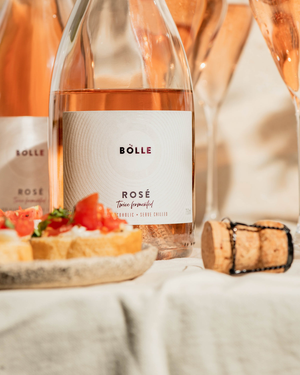 BOLLE Sparkling Rosé on a table with two glasses and the cork beside it